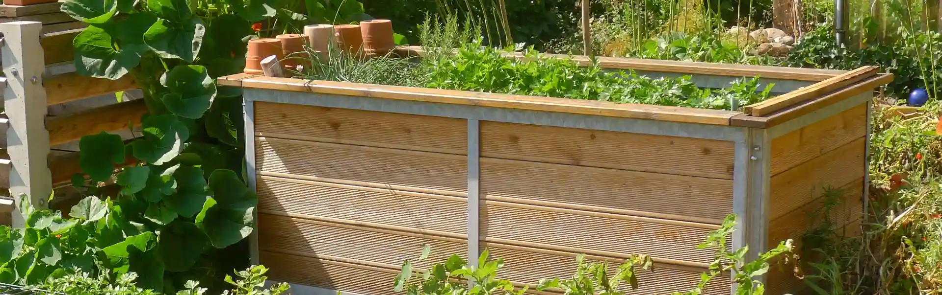 hochbeet aus lärchenholz und metallrahmen in kleinem garten